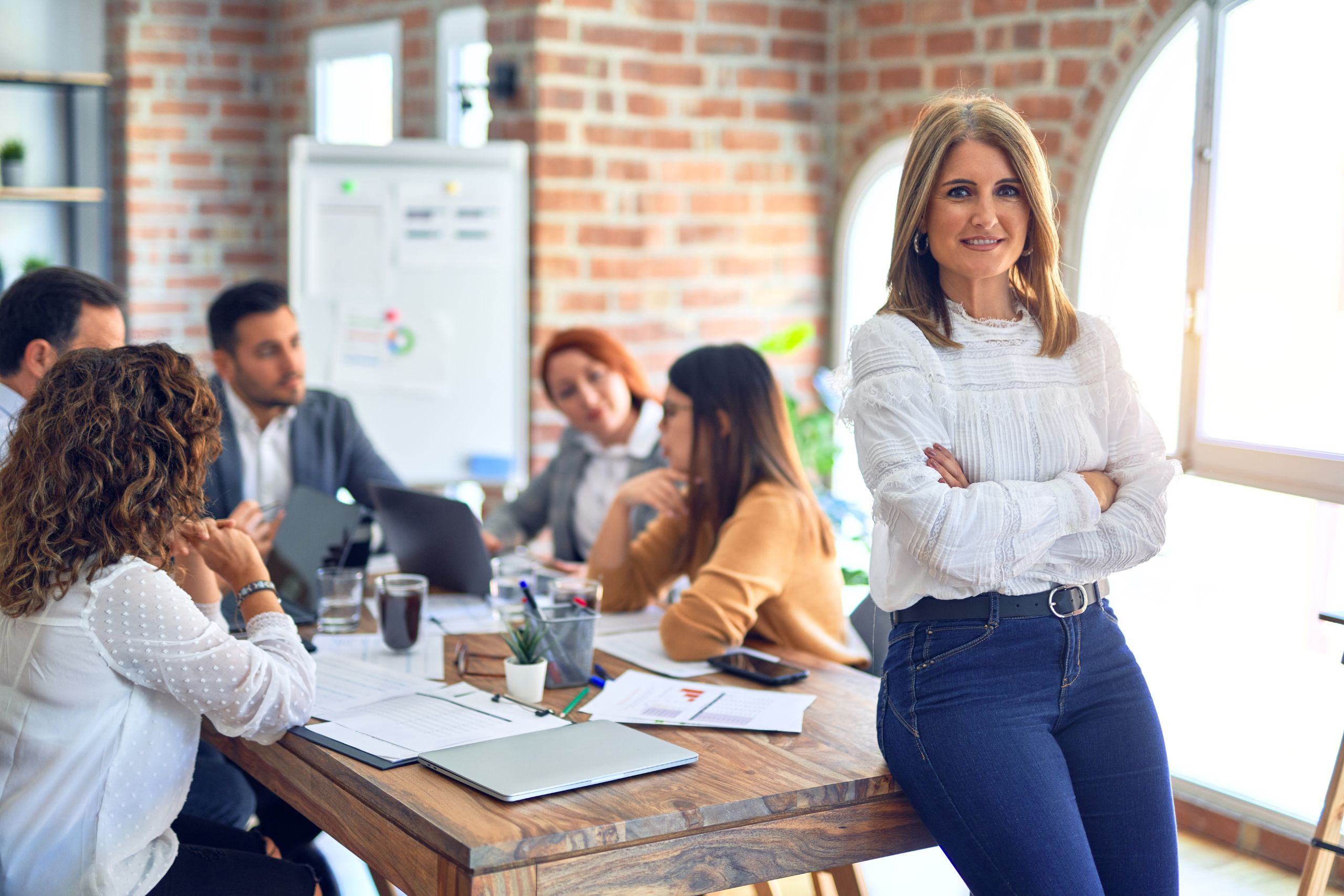 Team leader sitting on desk while members are discussing ideas